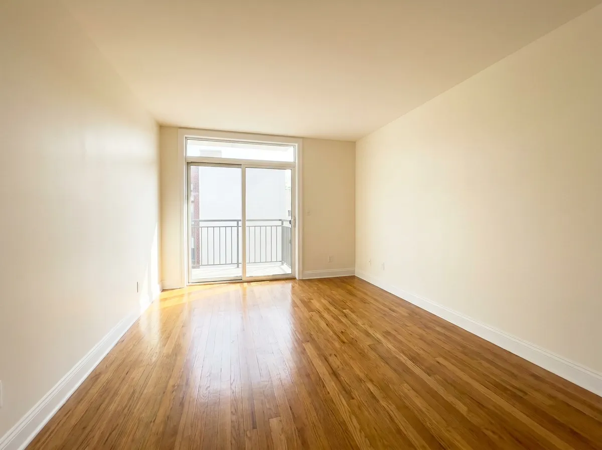 Sala de apartamento recién pintada en blanco cálido con puerta corrediza al balcón